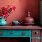 Teal vintage kitchenware on wooden sideboard with red wall backdrop.