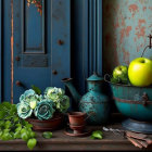 Green apples, aqua flowers, vintage watering can, teacup, keys on distressed blue backdrop