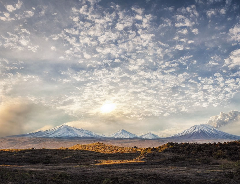 Snow-capped mountains in serene landscape with setting or rising sun