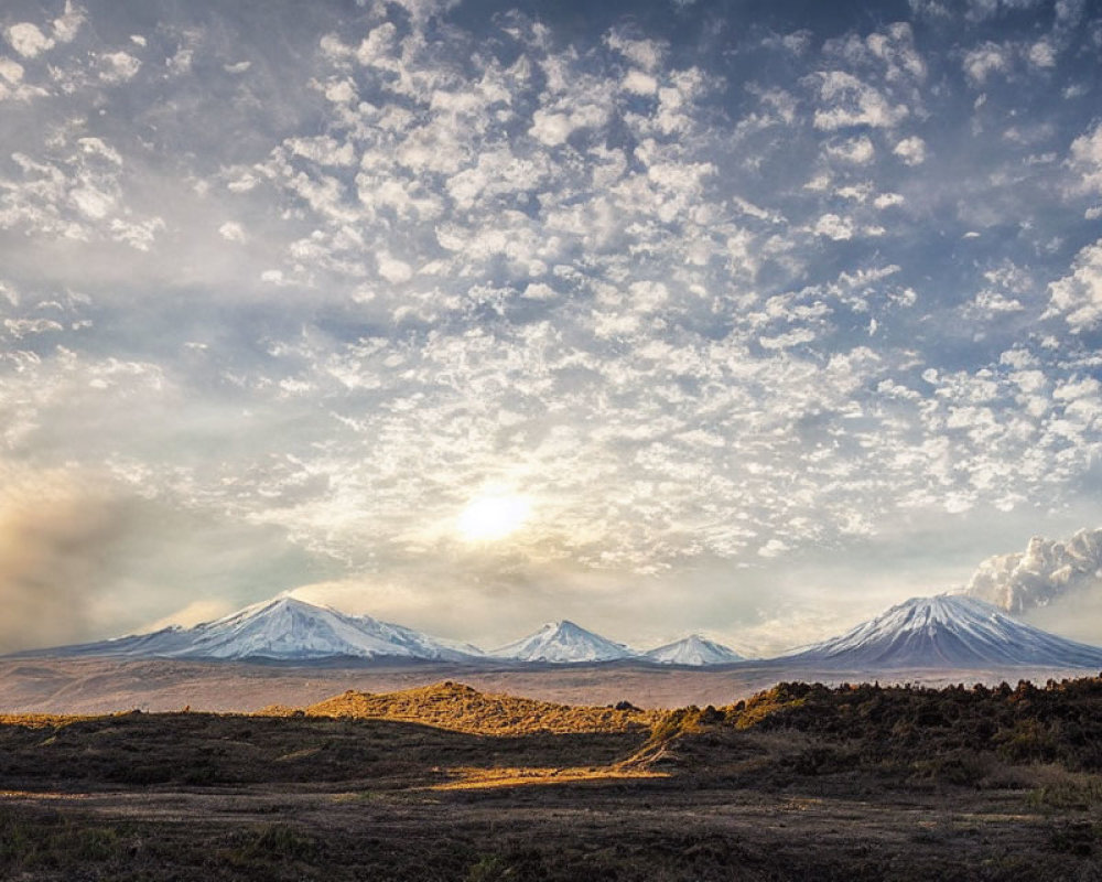 Snow-capped mountains in serene landscape with setting or rising sun