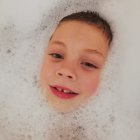 Child Bathing Surrounded by Soap Bubbles