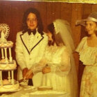 Luxurious vintage wedding scene with groom, two women in elegant gowns, golden trophy, and cake