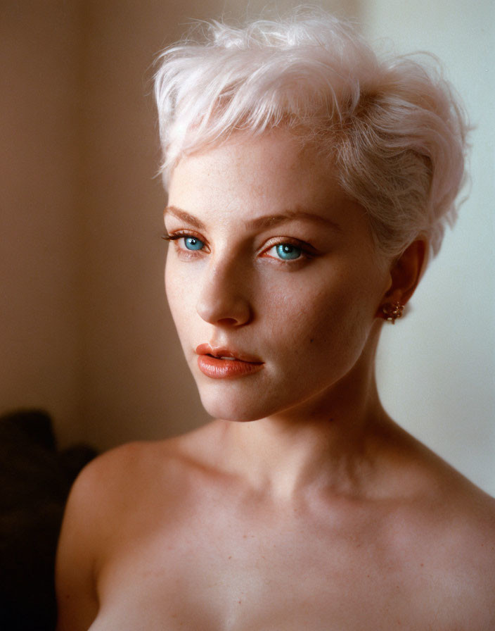 Portrait of person with short, curly platinum blonde hair and striking blue eyes