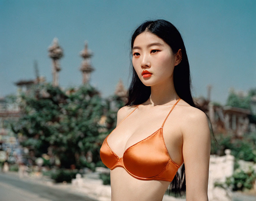 Woman in Orange Swimsuit Against Sunny Sky and Blurry Background