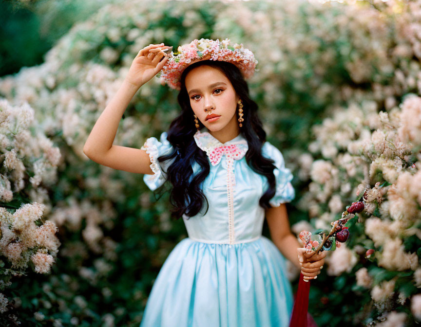 Young girl in vintage blue dress holding floral crown against lush green backdrop