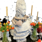 Ornate porcelain sculpture of woman with intricate hair details amid tulips, candles, and eggs on