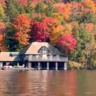 Tranquil twilight scene: Two-story house, autumn trees, peaceful water