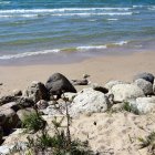 Rugged coastline watercolor painting with crashing waves, sandy beach, rocks, and greenery