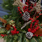 Christmas-themed arrangement with pine branches, baubles, red berries, and a large red flower on