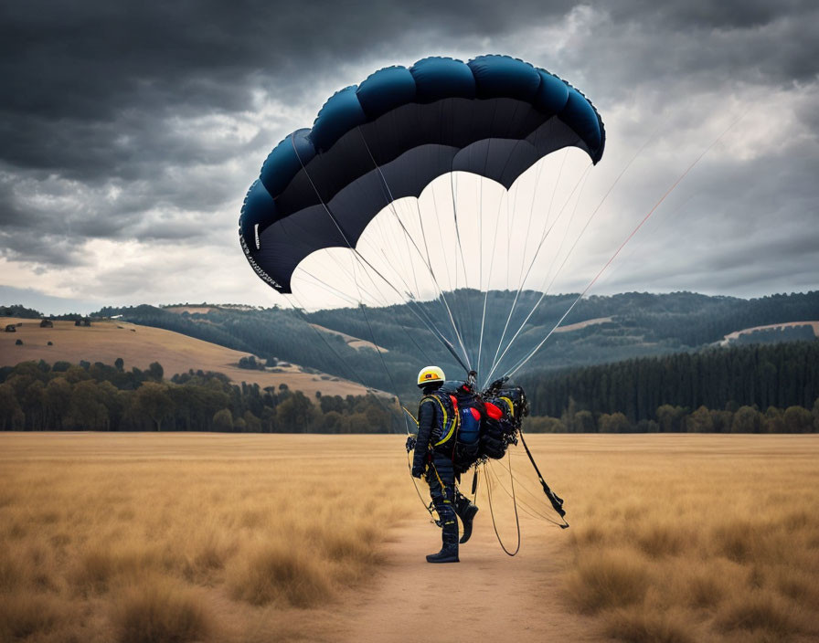 Parachutist landing in golden field with forested hills backdrop