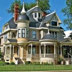 Victorian-style house with white gingerbread trim and pink facade in lush garden