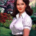 Brunette woman in white blouse against garden backdrop