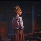 Vintage-dressed woman gazes upward in dimly lit room with classic furniture