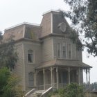 Victorian-style house in mist with intricate woodwork and trees