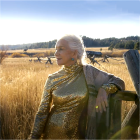 Elderly woman in golden dress smiles in serene field