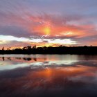 Vibrant orange and blue sunset sky over cascading waterfall and serene water surface