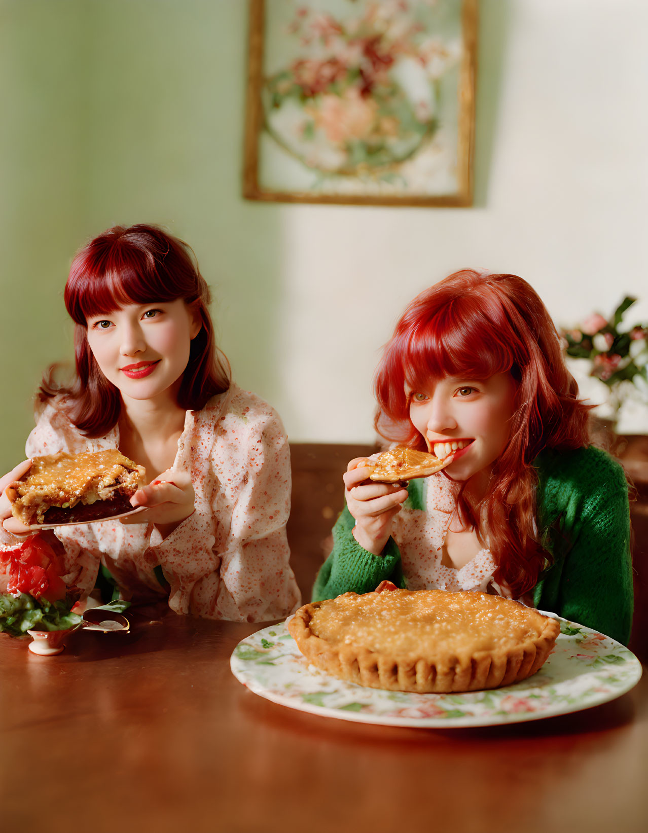 Two women with red hair enjoying pie at a table