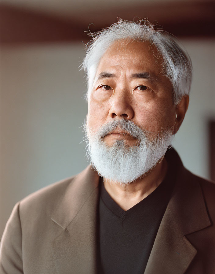 Older Asian man with gray beard and jacket portrait.