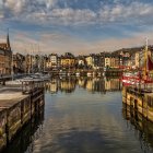 Picturesque European Harbor with Boats, Historic Buildings, and Dramatic Sky