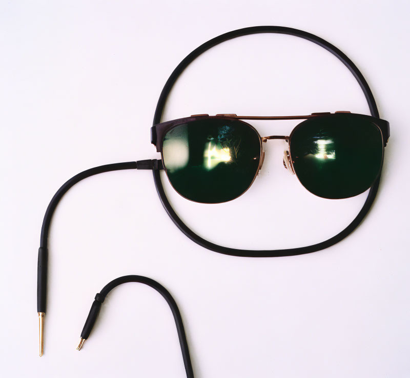 Round-framed sunglasses with detachable cable on white surface