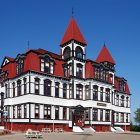 Detailed LEGO model of Victorian-style house with intricate rooflines, flower-filled balconies, and landscaped