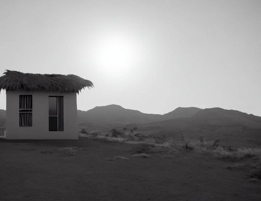 Thatched roof hut in desert landscape with hills and hazy sky