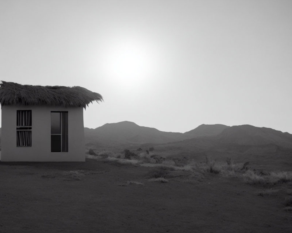 Thatched roof hut in desert landscape with hills and hazy sky