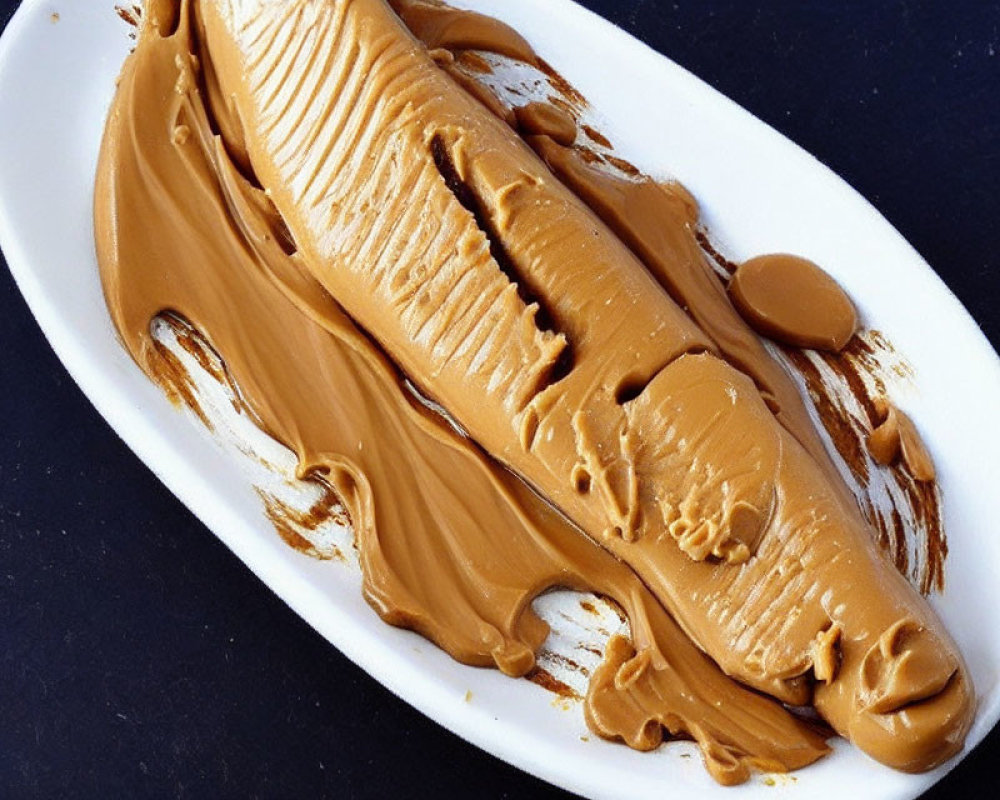 Creamy Peanut Butter Spread on Oval White Plate Against Dark Background