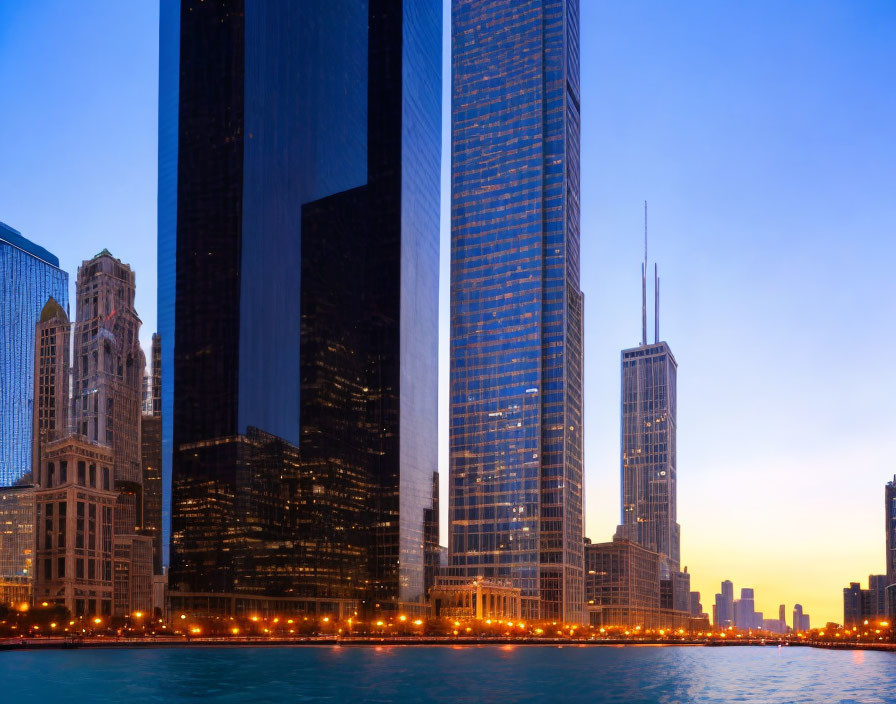 City skyline at dusk with illuminated buildings and water reflections