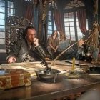 Man playing guitar on giant book in cluttered old room