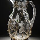 Intricately engraved glass pitcher with embedded clock face and metalwork