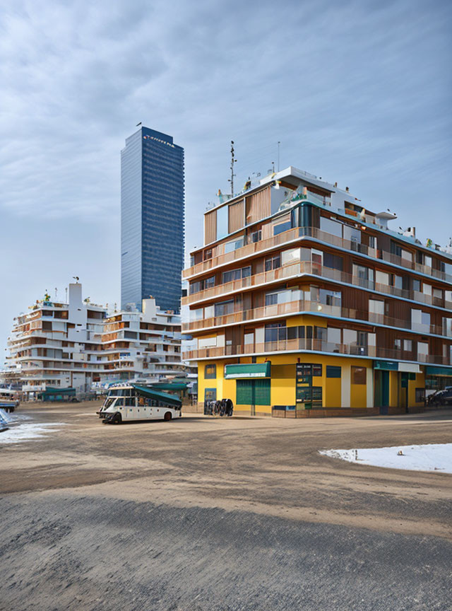 Colorful balconies contrast tall skyscraper, sandy ground, parked vehicle