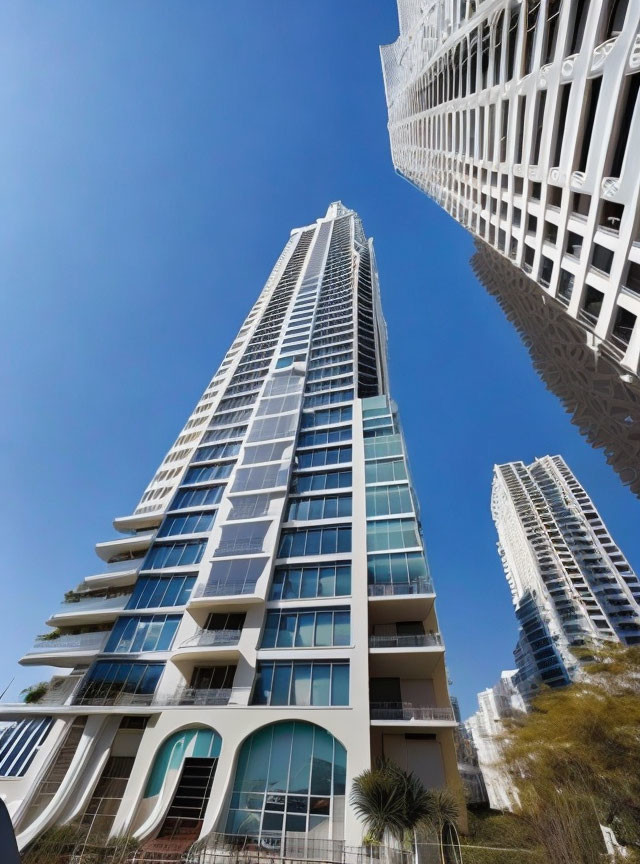 Modern white skyscraper with balconies against blue sky and other buildings