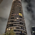 Cylindrical high-rise building with balconies at night, starry sky, airplanes