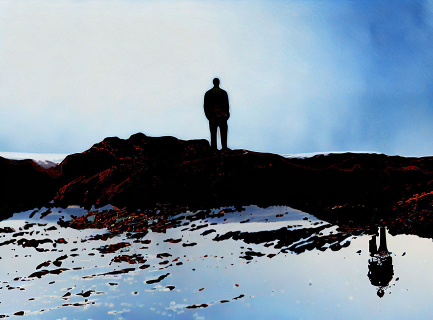 Silhouette of person on rocky shore under deep blue sky