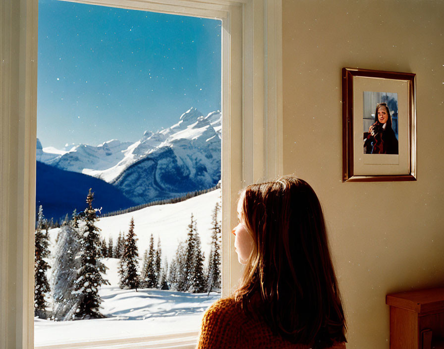 Woman admires snowy mountain view through window indoors.