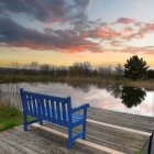 People on Blue Bench by Lake in Park at Sunset Facing City Skyline