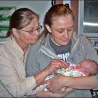 Elderly twin women cradle sleeping baby in serene sunset scene