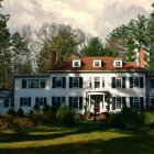 Snowy landscape surrounds Christmas-decorated two-story house