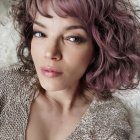 Curly-haired woman with glamorous makeup and floral embroidery attire