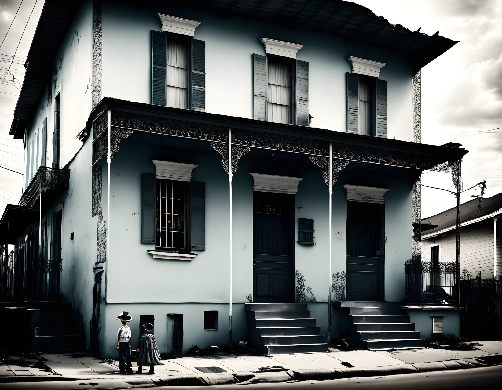 Vintage attired individuals outside historic two-story blue house with white balconies and shutters under moody