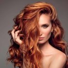 Vibrant curly red hair with colorful ornaments on soft brown background