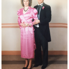 Formal Couple in Pink Dress and Navy Suit Against Wall