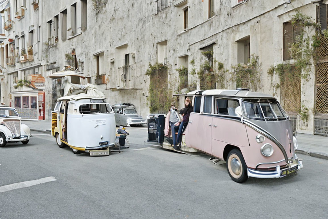 Vintage Volkswagen vans parked on street with person sitting in doorway