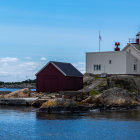 Coastal lighthouse on rugged cliffs under cloudy sky