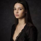 Portrait of young woman with dark hair and fair skin in dark dress on dark background