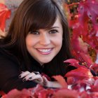 Digital portrait of a person with layered brown hair and red garment, featuring a subtle expression and black scarf