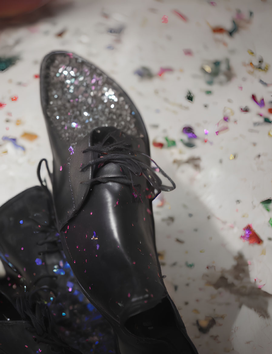 Black Dress Shoes with Glittery Detailing on Confetti-Covered Surface