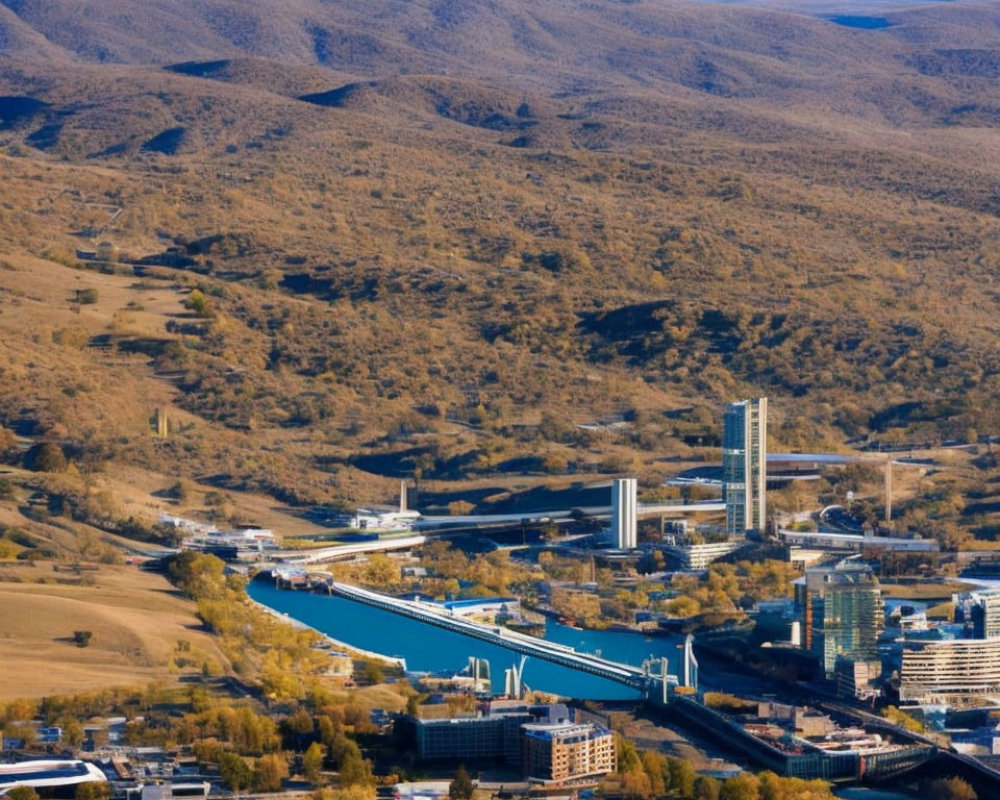 Industrial area with factories, blue canal, hills, and mountains in aerial view