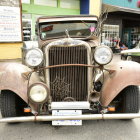 Classic Vintage Car with Round Headlights and Ornate Grille on Cobblestone Street